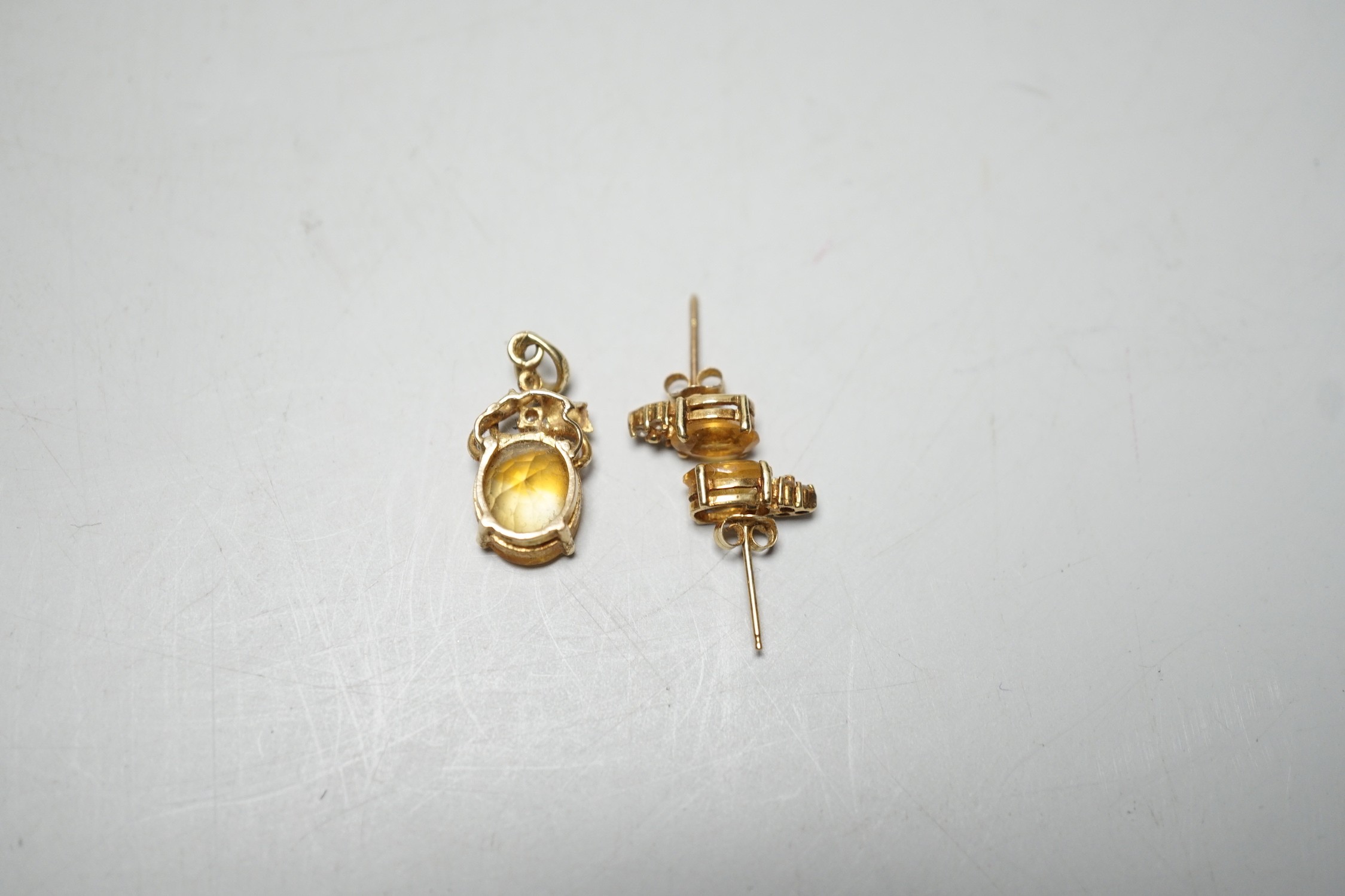 A modern 14k, citrine and diamond chip set pendant, 15mm and a pair of matching ear studs, gross weight 3.1 grams.